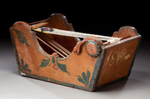 Box type tape loom with date of 1849 nicknamed the "cradle loom." Collection of and photograph from Versterheim Norwegian-American Museum.